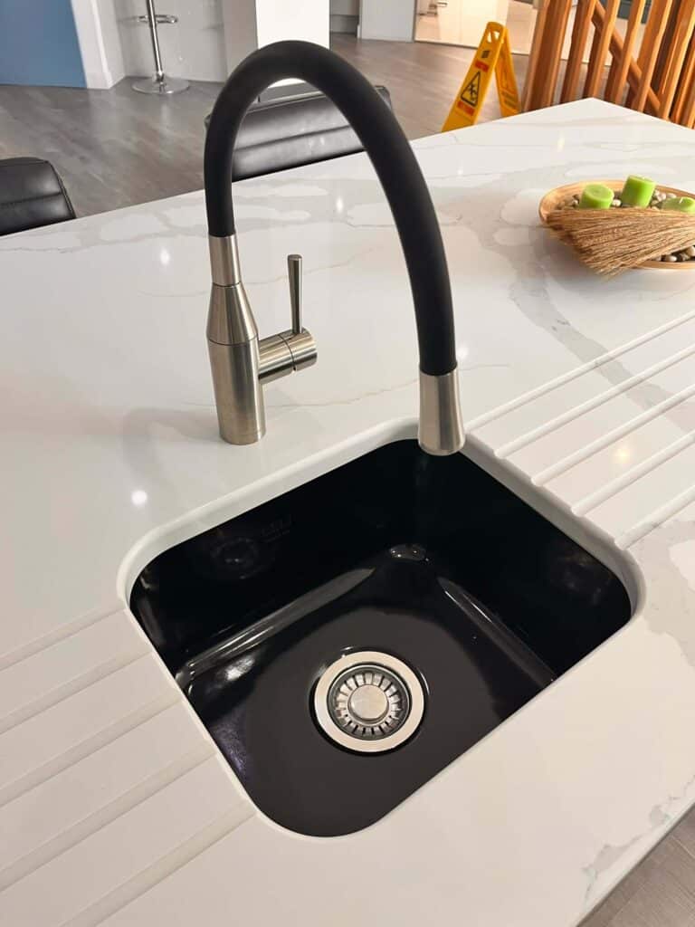 a ceramic sink at New Design Kitchens showroom to demonstrate ceramic sink care